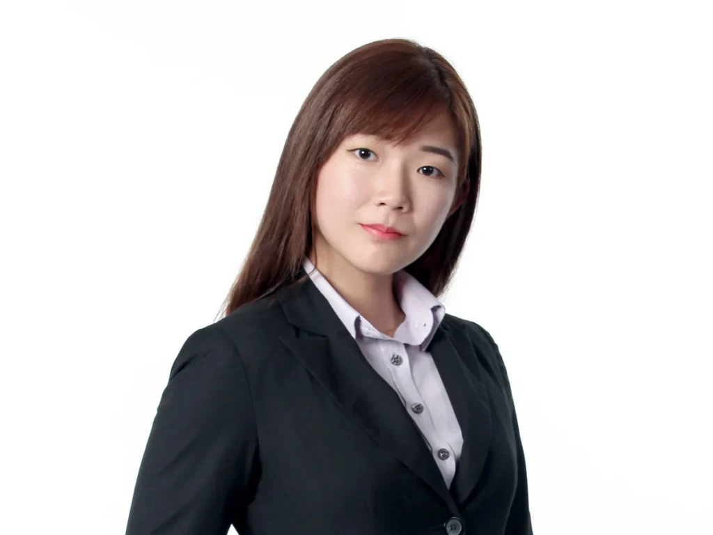 Yin Sinn in a black blazer and white shirt, hand in pocket, in a studio