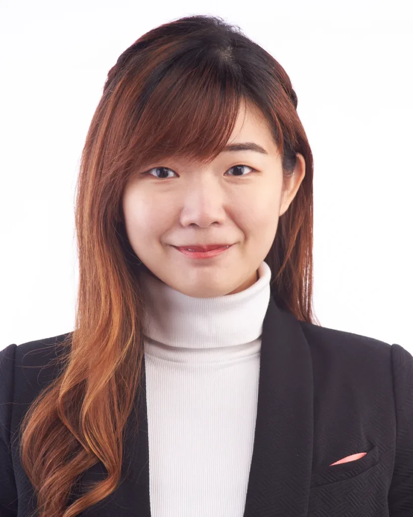 Close-up portrait of Yin Sinn smiling, in a black blazer and white polo neck