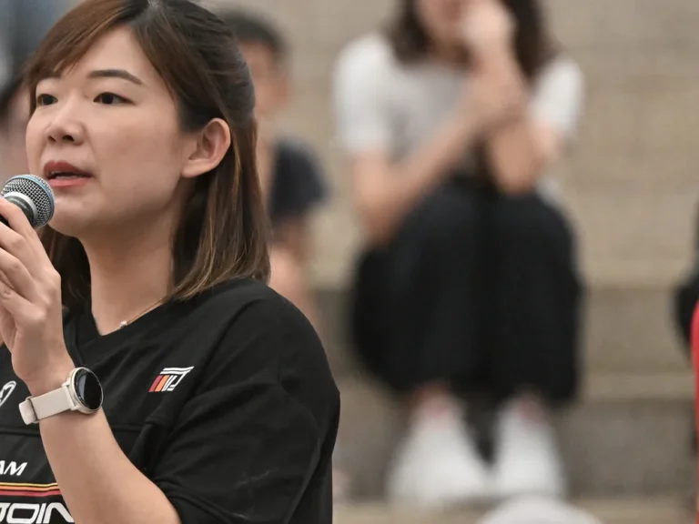 Yin Sinn holding a microphone while hosting a live event